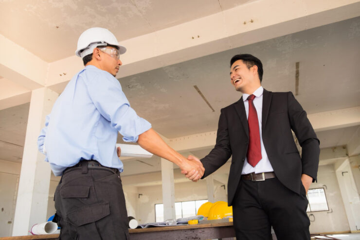 A construction site meeting between the contractor and the client shaking hands