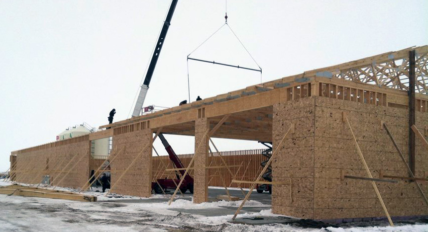 Workers lifting wooden beams with a crane at a commercial construction site