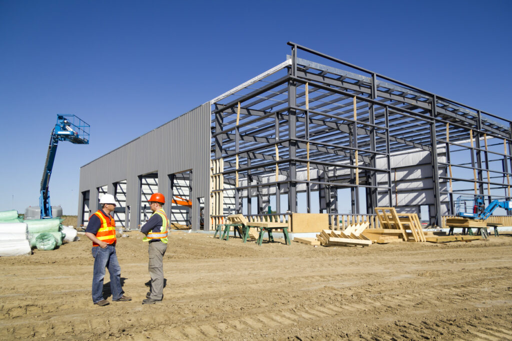 Two contractors discuss progress at a large commercial construction site