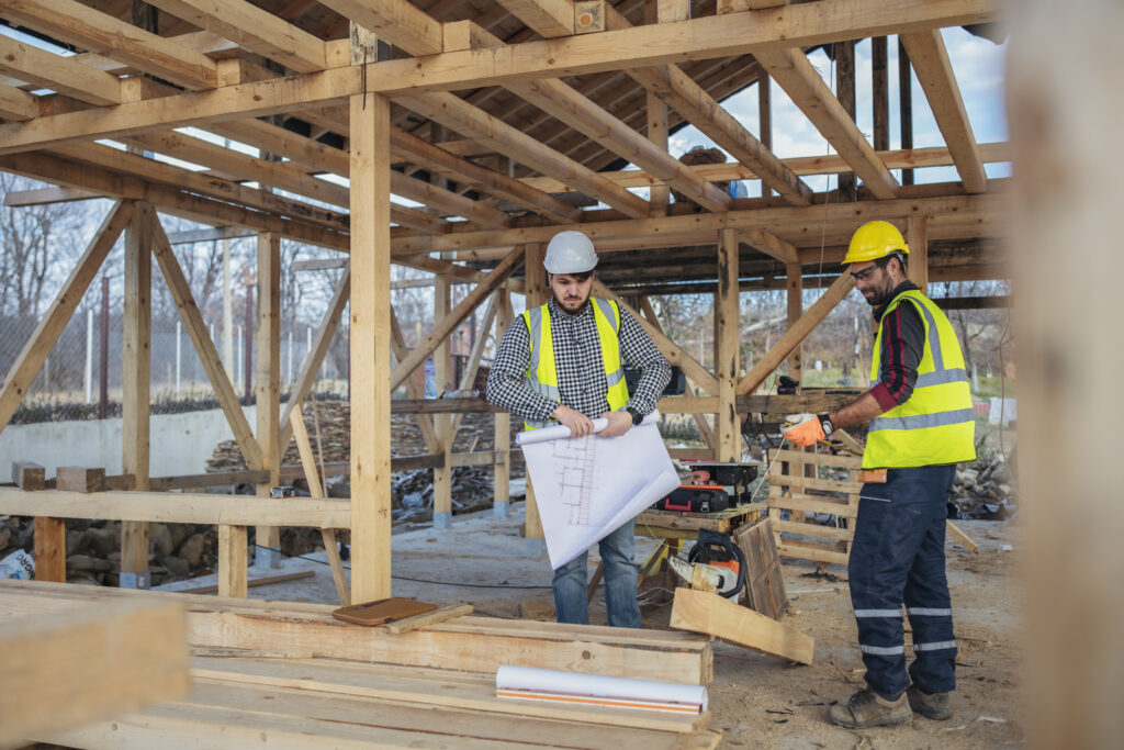 Construction workers reviewing plan at wood frame site