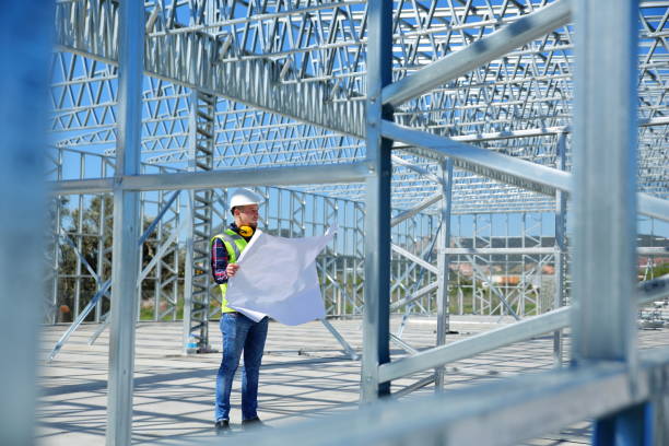 Construction worker reviewing plans inside steel framework