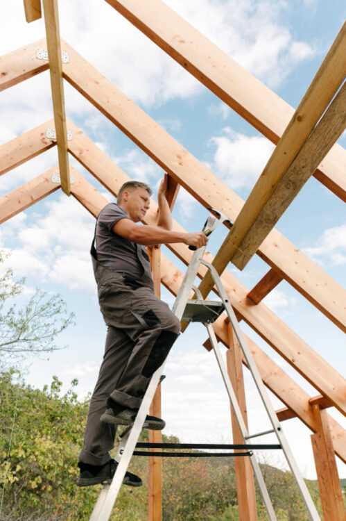 Worker on a ladder constructing a pole barn frame.