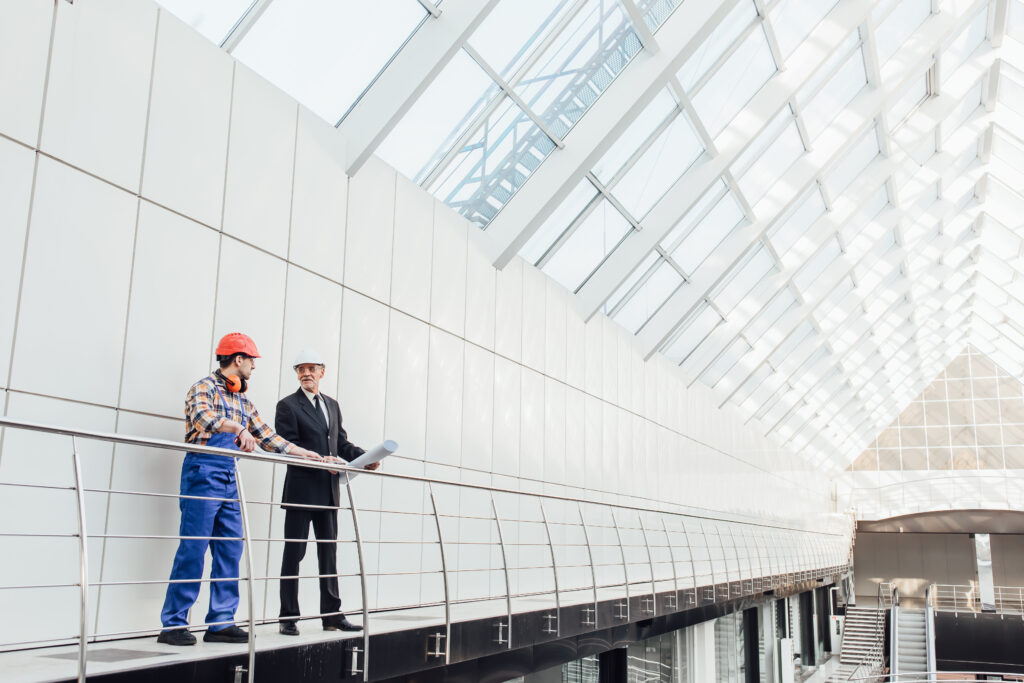 Architects reviewing plans inside a large modern steel building structure.